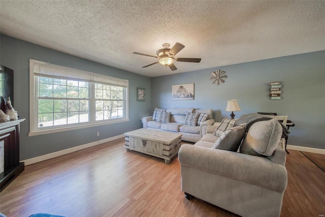 living room with light hardwood / wood-style floors, a textured ceiling, and ceiling fan