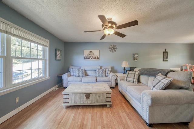 living room with light hardwood / wood-style floors, a textured ceiling, and ceiling fan