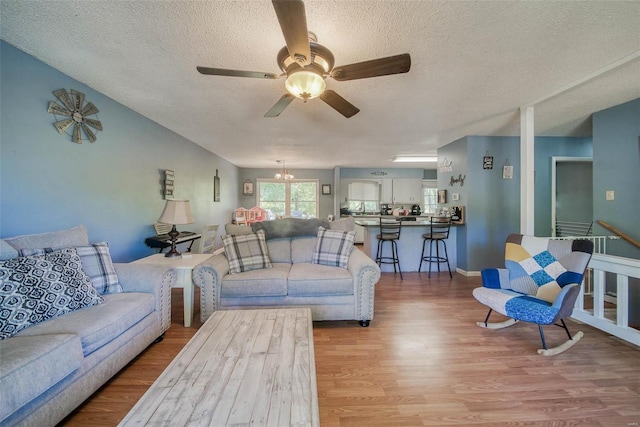 living room with wood-type flooring, a textured ceiling, and ceiling fan with notable chandelier