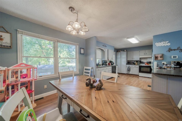 dining area featuring light hardwood / wood-style floors, a textured ceiling, and a chandelier