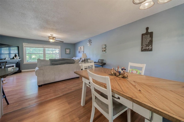 dining space with ceiling fan, a textured ceiling, and hardwood / wood-style floors