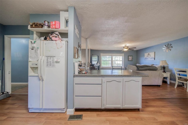 kitchen with a textured ceiling, white cabinetry, white refrigerator with ice dispenser, and light hardwood / wood-style flooring