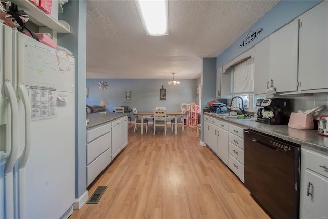 kitchen featuring dishwasher, sink, pendant lighting, white refrigerator, and white cabinets