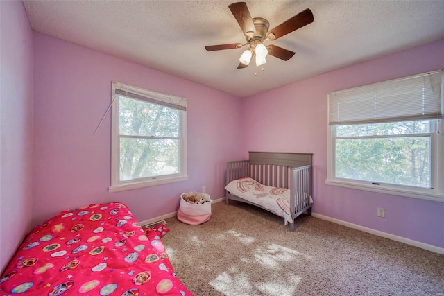 bedroom with multiple windows, carpet floors, a textured ceiling, and ceiling fan