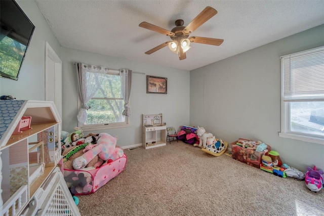 game room featuring ceiling fan, a textured ceiling, and plenty of natural light