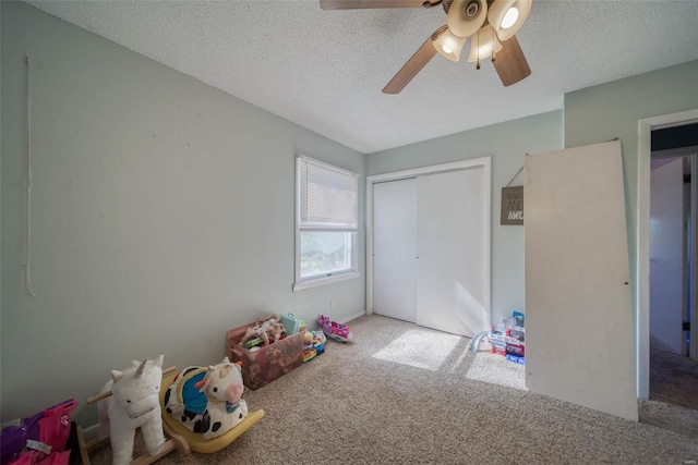 game room featuring a textured ceiling, carpet flooring, and ceiling fan