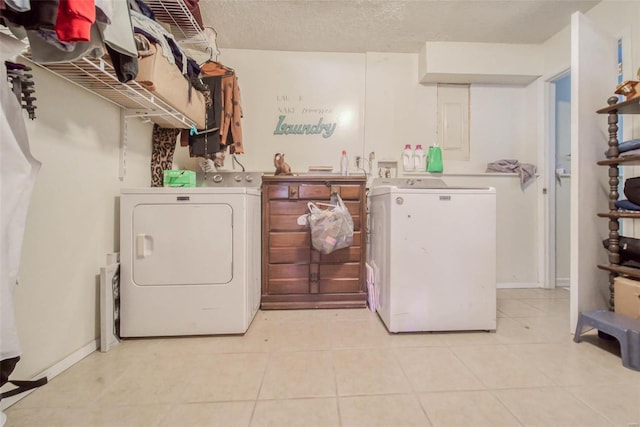 clothes washing area with a textured ceiling, washing machine and dryer, and light tile patterned floors