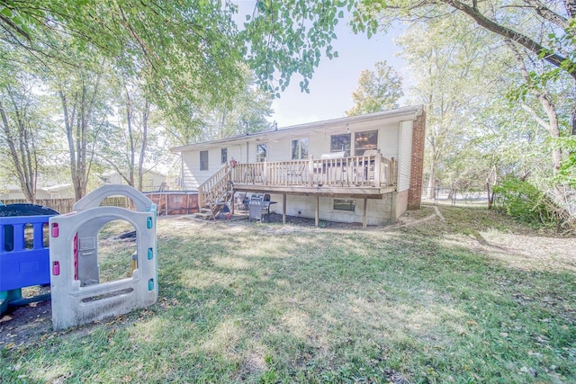 rear view of property featuring a wooden deck and a lawn