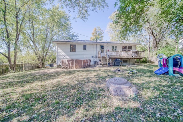 rear view of house featuring a deck, a lawn, and a fire pit