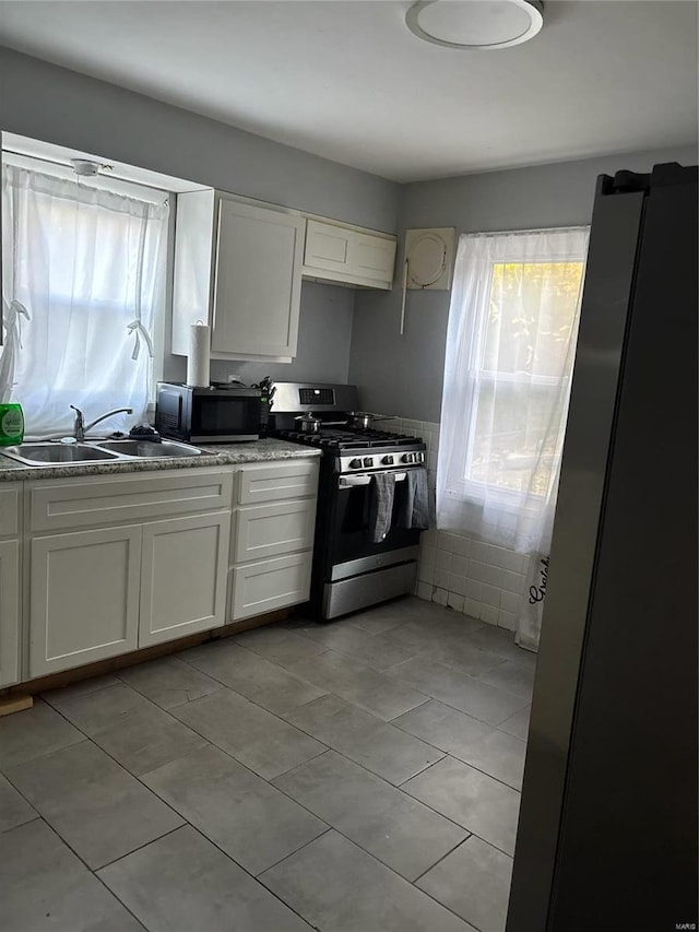 kitchen featuring light tile patterned floors, white cabinetry, sink, and appliances with stainless steel finishes