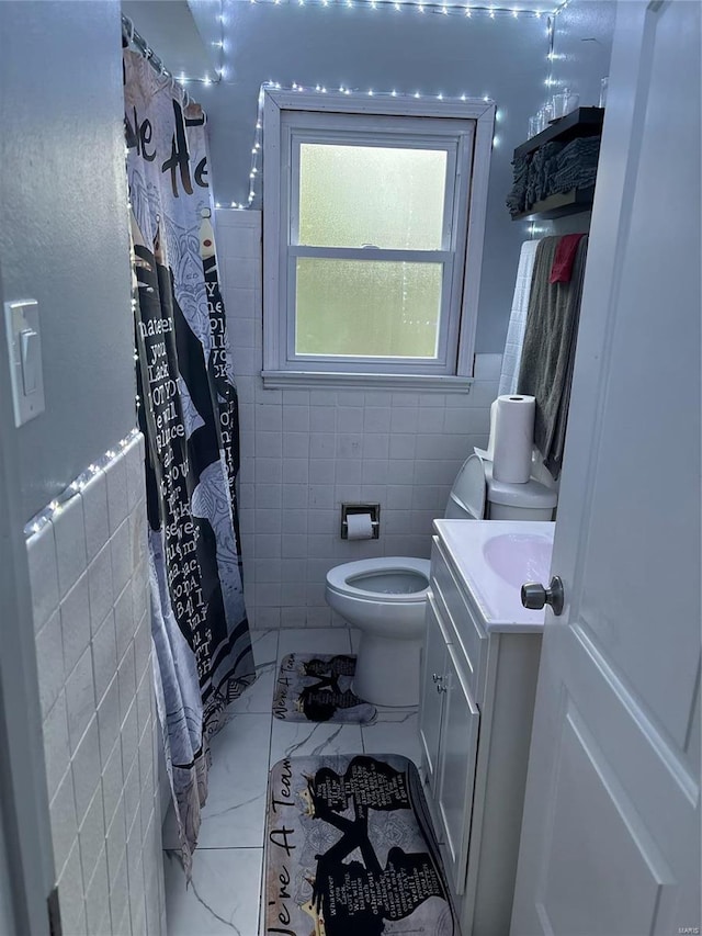 bathroom with walk in shower, vanity, tile walls, and toilet