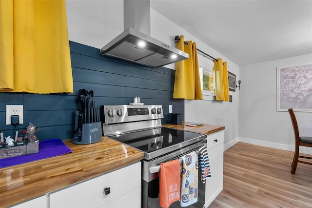 kitchen featuring electric range, wood counters, white cabinetry, and range hood