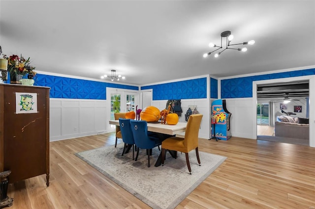 dining room featuring french doors, an inviting chandelier, light hardwood / wood-style flooring, and ornamental molding