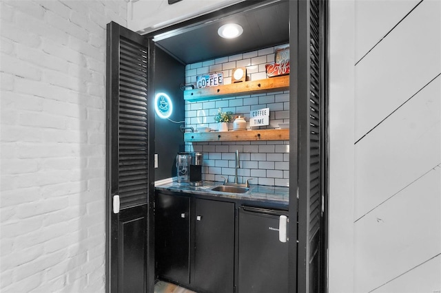 bar featuring decorative backsplash, brick wall, and sink