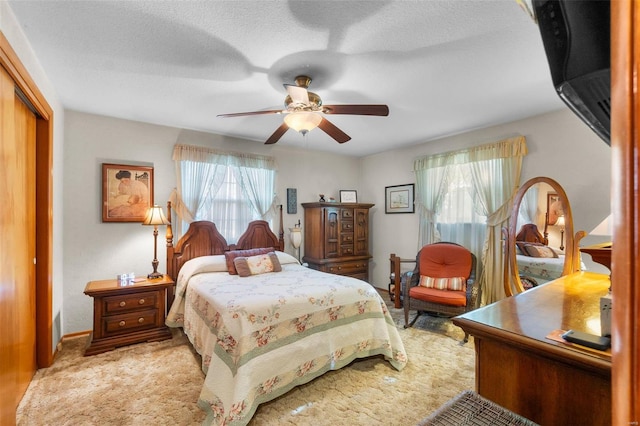 bedroom with a closet, ceiling fan, light carpet, and a textured ceiling