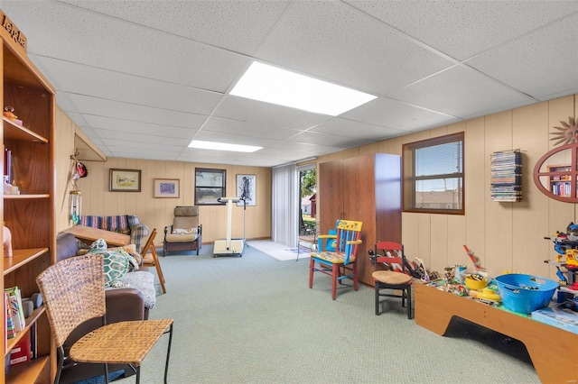 playroom featuring a paneled ceiling, wood walls, and carpet