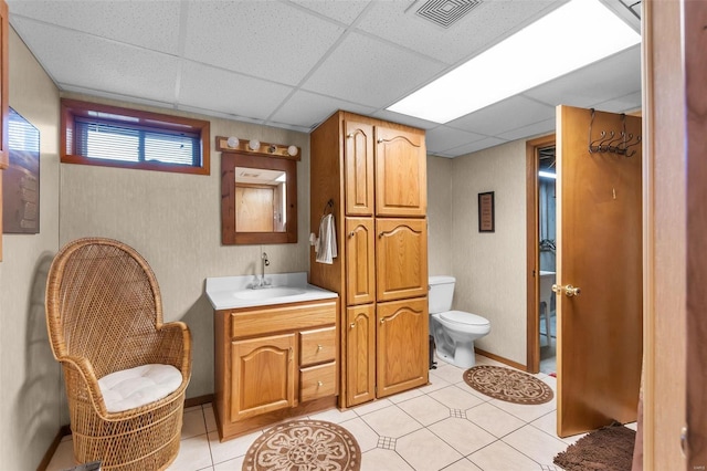 bathroom with vanity, toilet, tile patterned floors, and a paneled ceiling