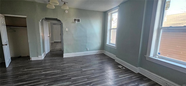 unfurnished bedroom with a closet, dark wood-type flooring, and multiple windows