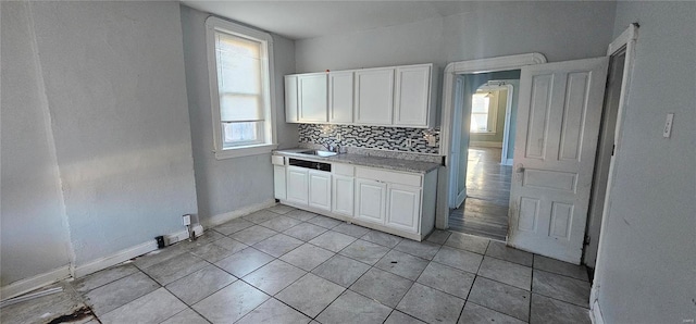 kitchen with white cabinets, decorative backsplash, light tile patterned floors, and sink