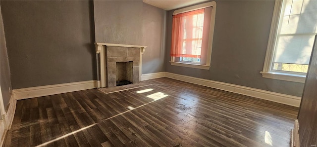 unfurnished living room with a tile fireplace, hardwood / wood-style flooring, and a wealth of natural light