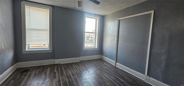 spare room with a healthy amount of sunlight, a textured ceiling, ceiling fan, and dark wood-type flooring