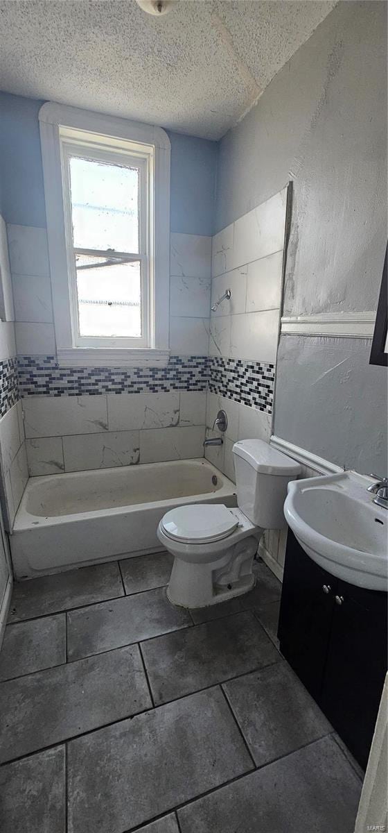 full bathroom featuring vanity, tiled shower / bath combo, a textured ceiling, and toilet