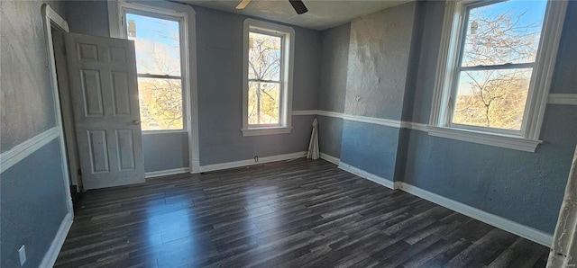 empty room featuring dark wood-type flooring, ceiling fan, and a healthy amount of sunlight