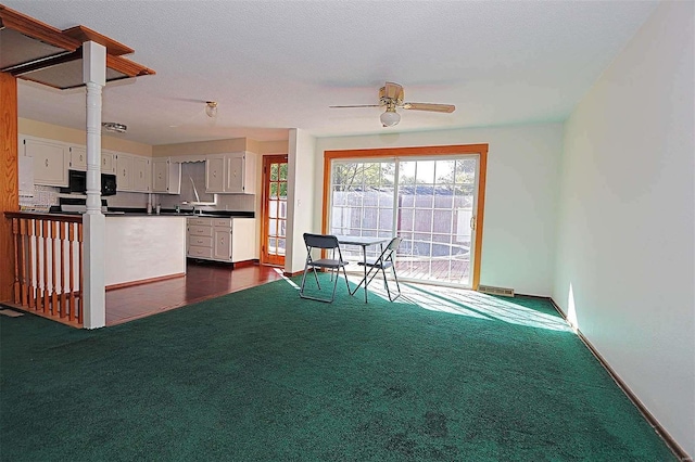 unfurnished living room with dark colored carpet, a textured ceiling, and ceiling fan