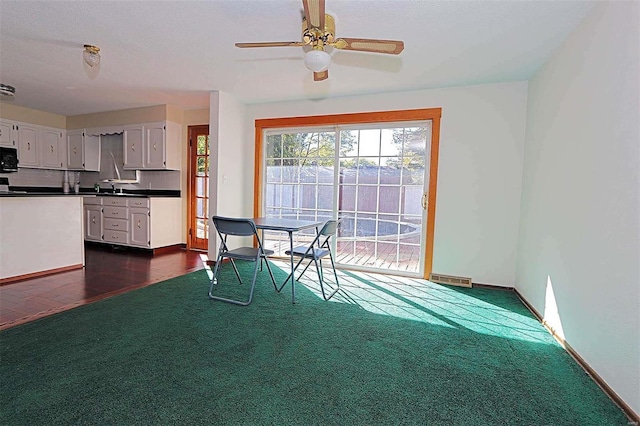 unfurnished dining area with dark carpet, sink, and ceiling fan