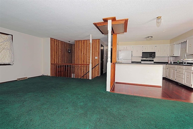 kitchen featuring white cabinetry, a textured ceiling, white refrigerator, and dark colored carpet