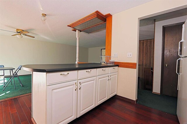 kitchen featuring kitchen peninsula, white cabinetry, a textured ceiling, and dark hardwood / wood-style flooring