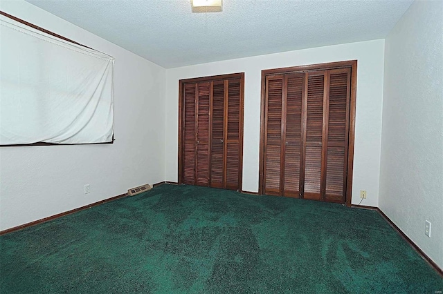 unfurnished bedroom with a textured ceiling, multiple closets, and carpet flooring