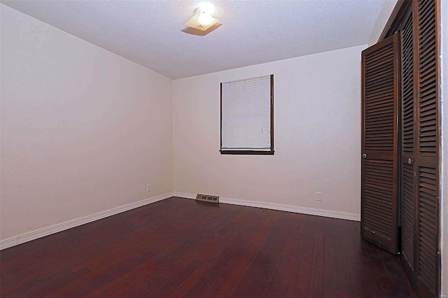 unfurnished bedroom with a closet, a textured ceiling, and dark hardwood / wood-style flooring