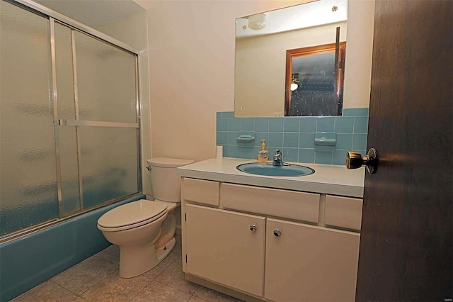 full bathroom with decorative backsplash, toilet, tile patterned flooring, bath / shower combo with glass door, and vanity