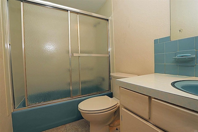 full bathroom featuring toilet, bath / shower combo with glass door, vanity, and tile patterned floors