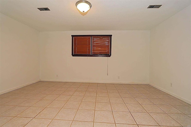 empty room featuring a textured ceiling and light tile patterned floors