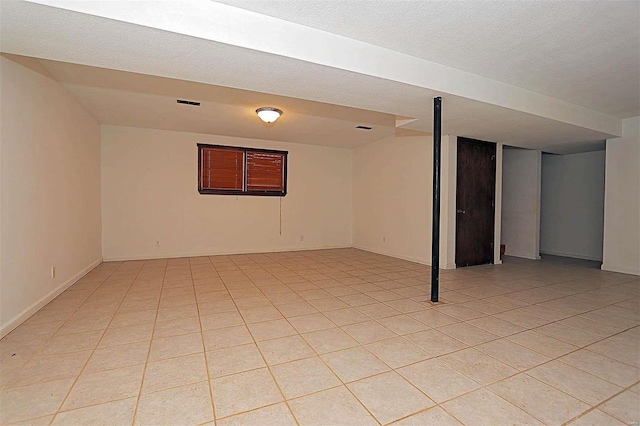 basement featuring a textured ceiling and light tile patterned flooring