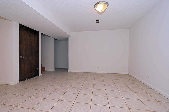 empty room with light tile patterned flooring and a textured ceiling