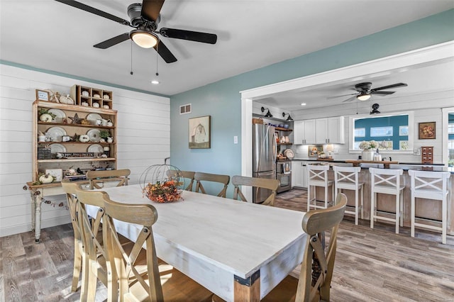 dining space featuring wooden walls and light wood-type flooring