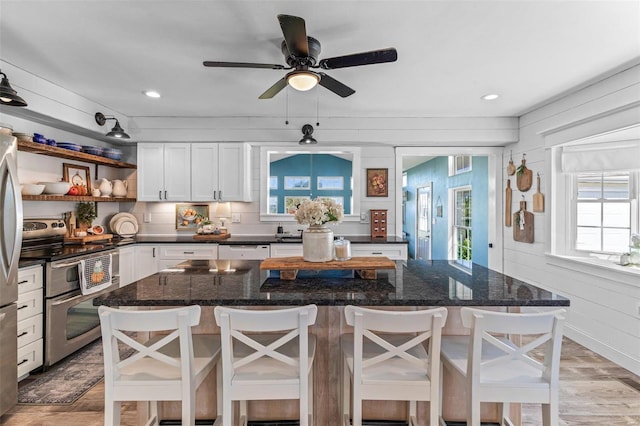 kitchen featuring a wealth of natural light, wood walls, a kitchen bar, and appliances with stainless steel finishes