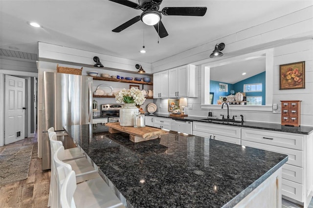 kitchen with a center island, lofted ceiling, white cabinets, sink, and light hardwood / wood-style floors