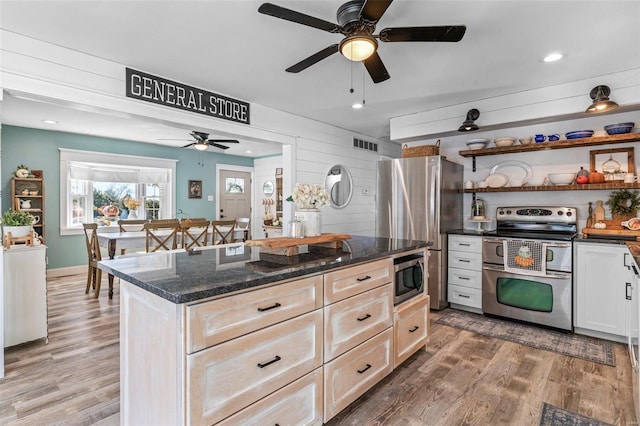 kitchen featuring hardwood / wood-style floors, stainless steel appliances, dark stone countertops, and wood walls