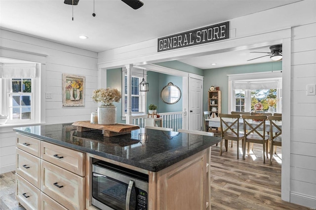 kitchen with a center island, hardwood / wood-style flooring, dark stone counters, and wood walls