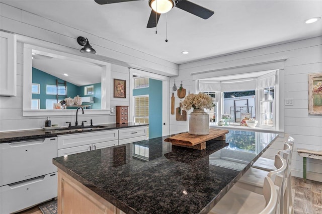 kitchen featuring sink, dishwasher, white cabinets, light hardwood / wood-style floors, and a kitchen island