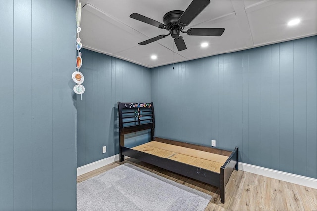 bedroom featuring ceiling fan, hardwood / wood-style floors, and wood walls