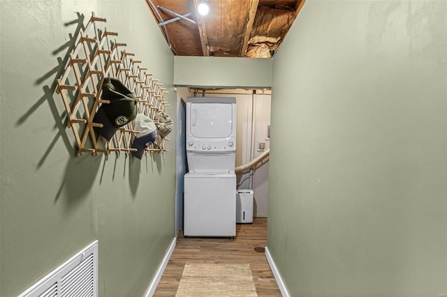 laundry area featuring light hardwood / wood-style floors and stacked washer / dryer