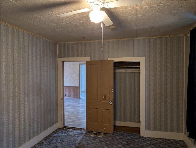 unfurnished bedroom with a closet, dark carpet, and ceiling fan