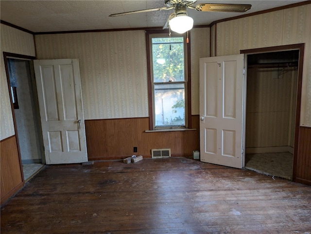 unfurnished bedroom with wooden walls, hardwood / wood-style floors, a closet, and ceiling fan