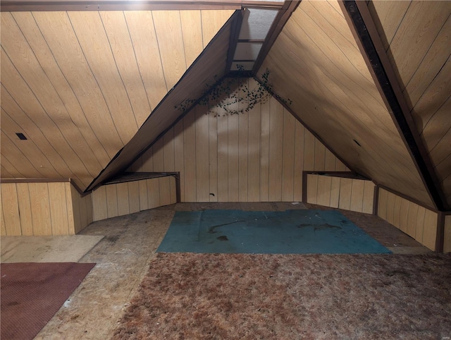 additional living space featuring vaulted ceiling and wood walls