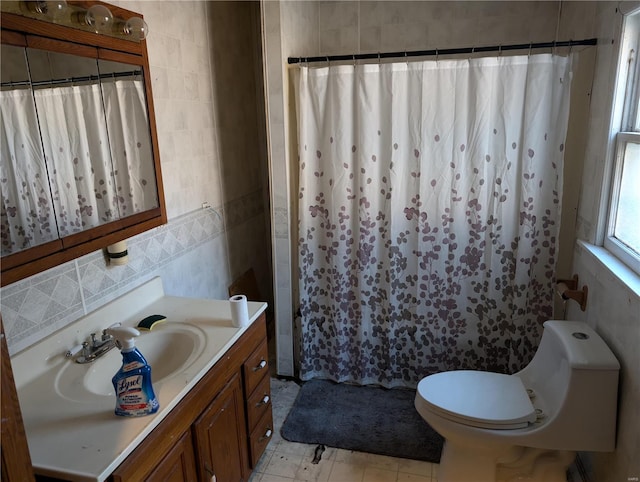 bathroom with tile patterned floors, toilet, a shower with shower curtain, tile walls, and vanity